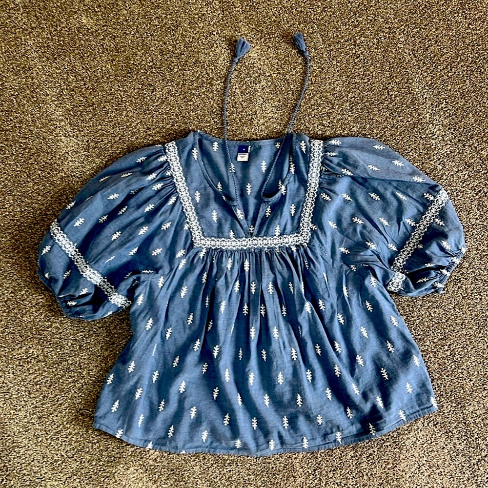 Denim blue peasant top with pattern in white stitching.
